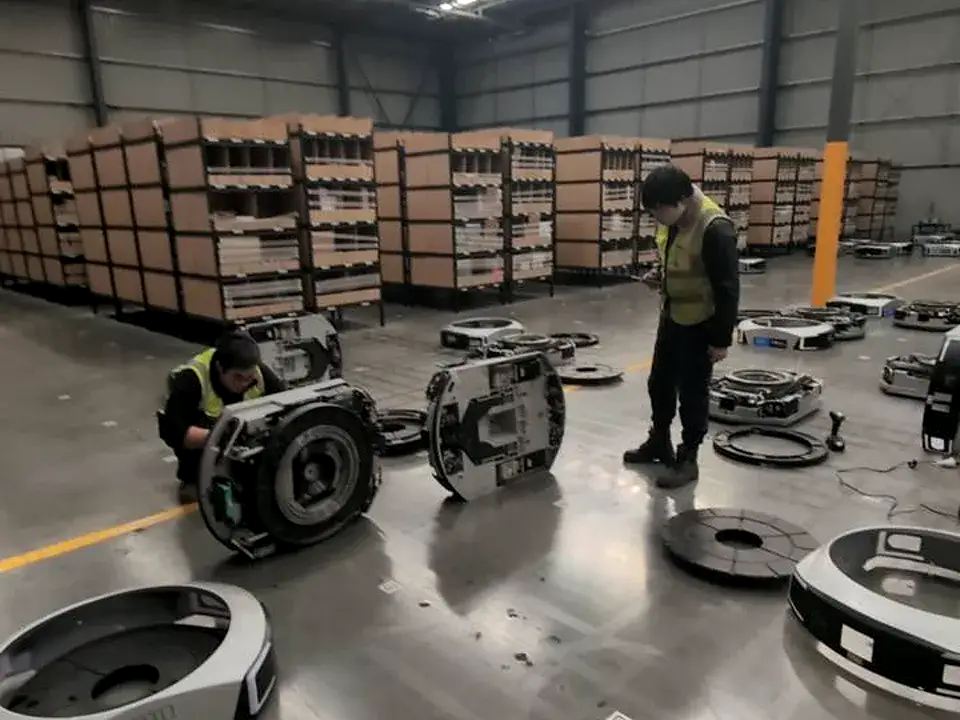 Field technicians inspecting opened Geek+ mobile robots